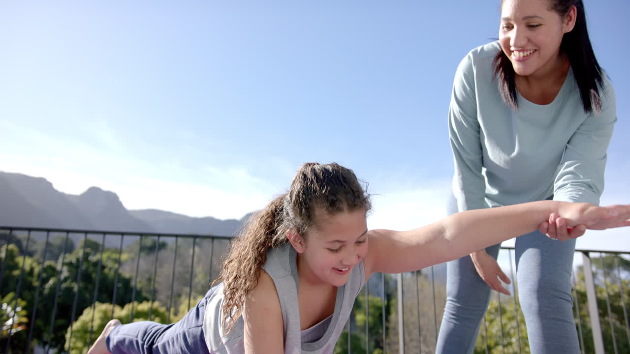 행복한 혼혈 어머니와 딸이 이 나는 날 테라스에서 요가를 연습하고, 느린 동작, 복사 공간