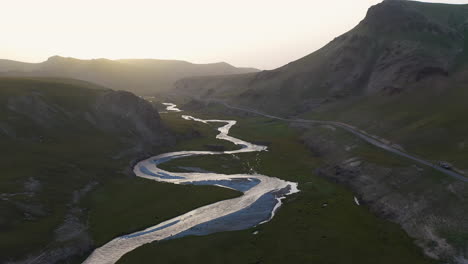 epic cinematic revealing drone shot of a river leading into the kel-suu lake during golden hour in kyrgyzstan