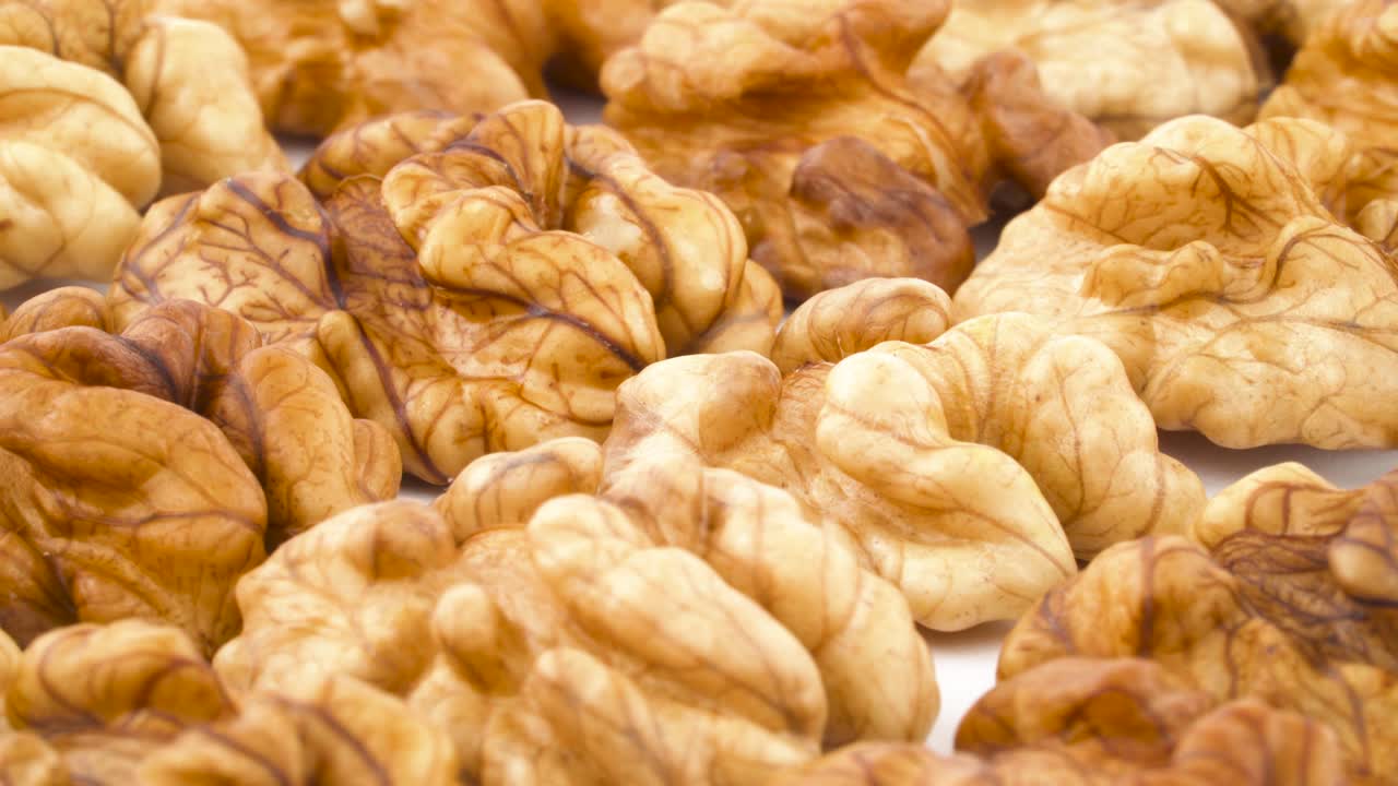 Heap of walnuts the shell. Rotating on the turntable isolated on the white background. Close up. Macro.