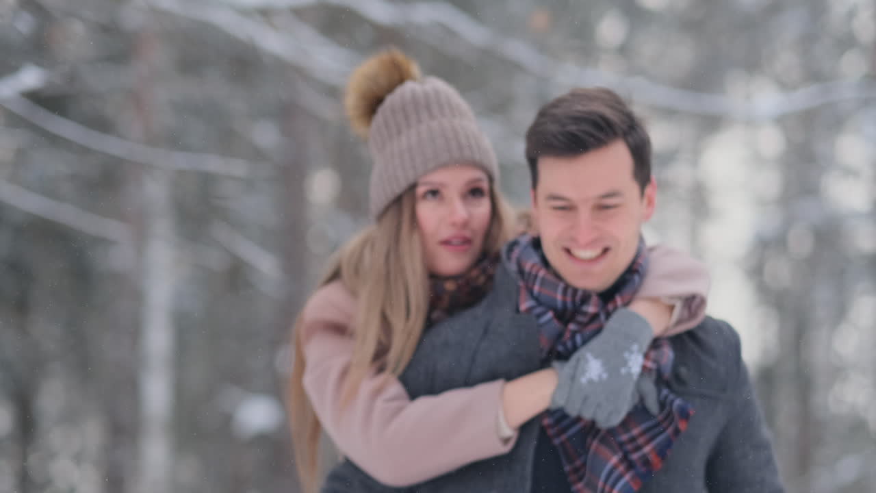 눈 덮인 겨울에 야외에서 즐겁게 웃고 웃는 젊은 아름다운 커플