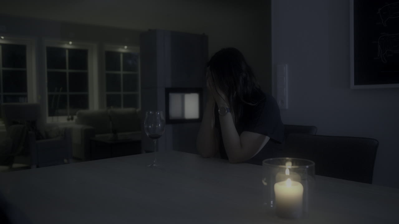 Halvnært billede af en kvinde med et tomt glas, der udtrykker stærk angst eller depression om natten, med glidende panorering