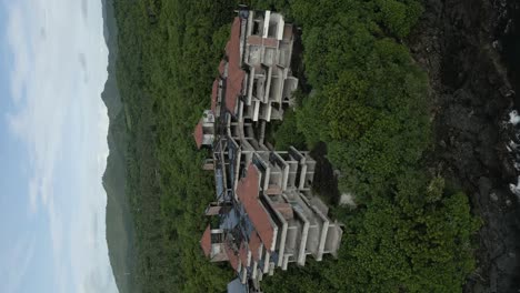 toma panorámica vertical de drones aéreos de un hotel abandonado en la naturaleza verde de indonesia