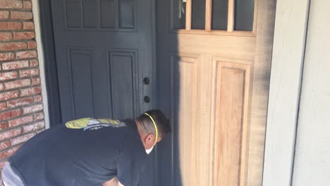 portrait of professional painter using airless sprayer to paint house doors with primer