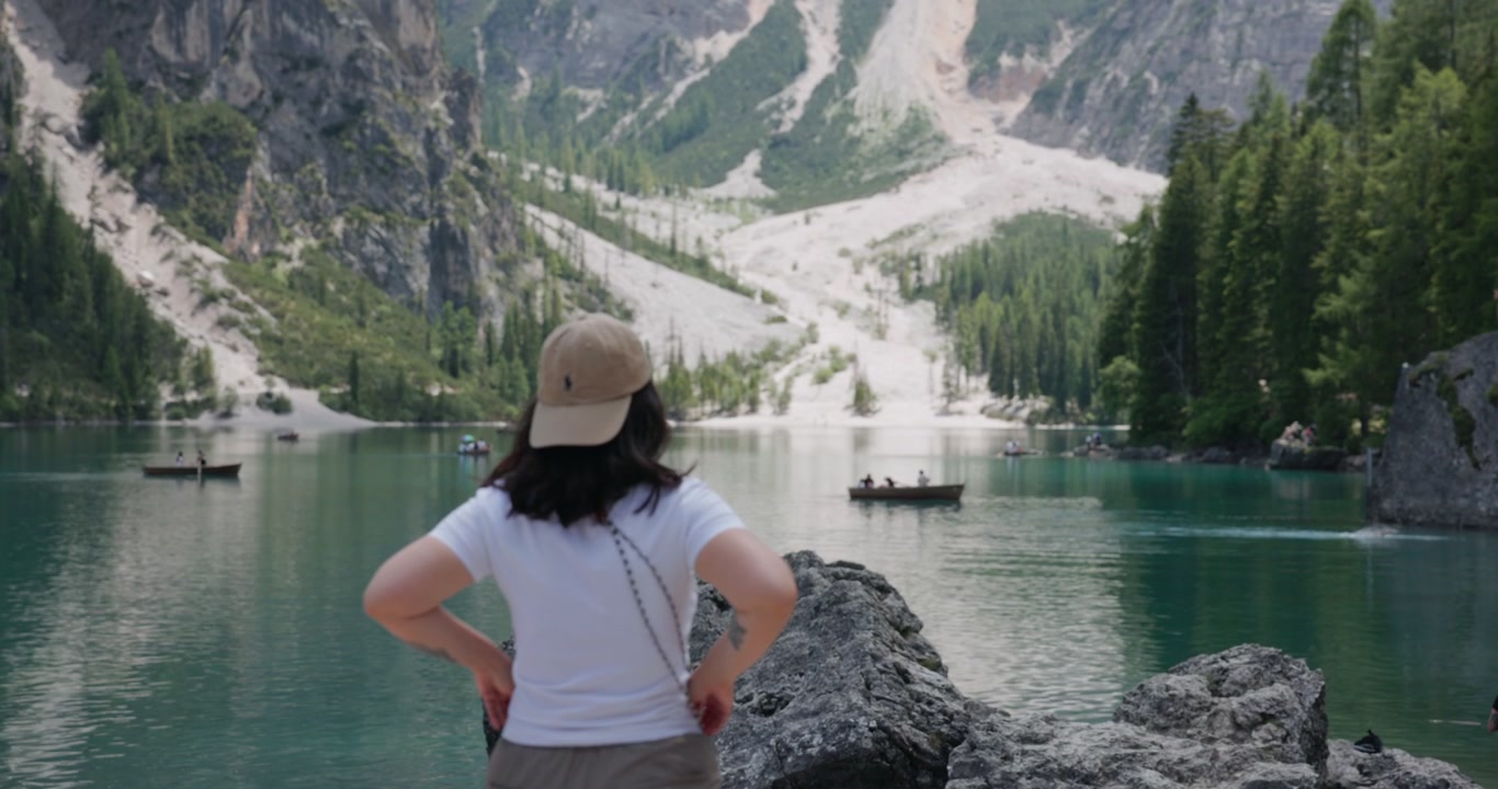 Młoda kobieta podziwia naturalny krajobraz wzdłuż brzegów Lago di Braies we włoskich Dolomitach. Ujęcie w zwolnionym tempie