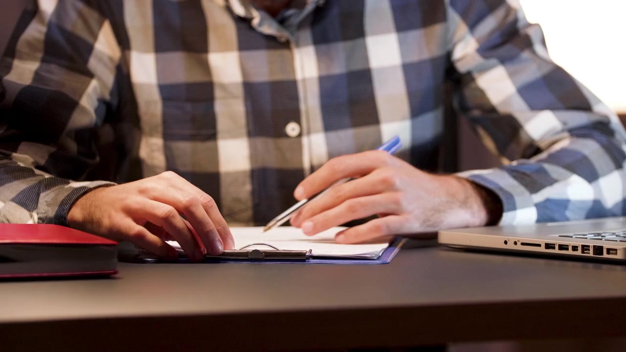 Uomo che esamina e firma documenti a una scrivania