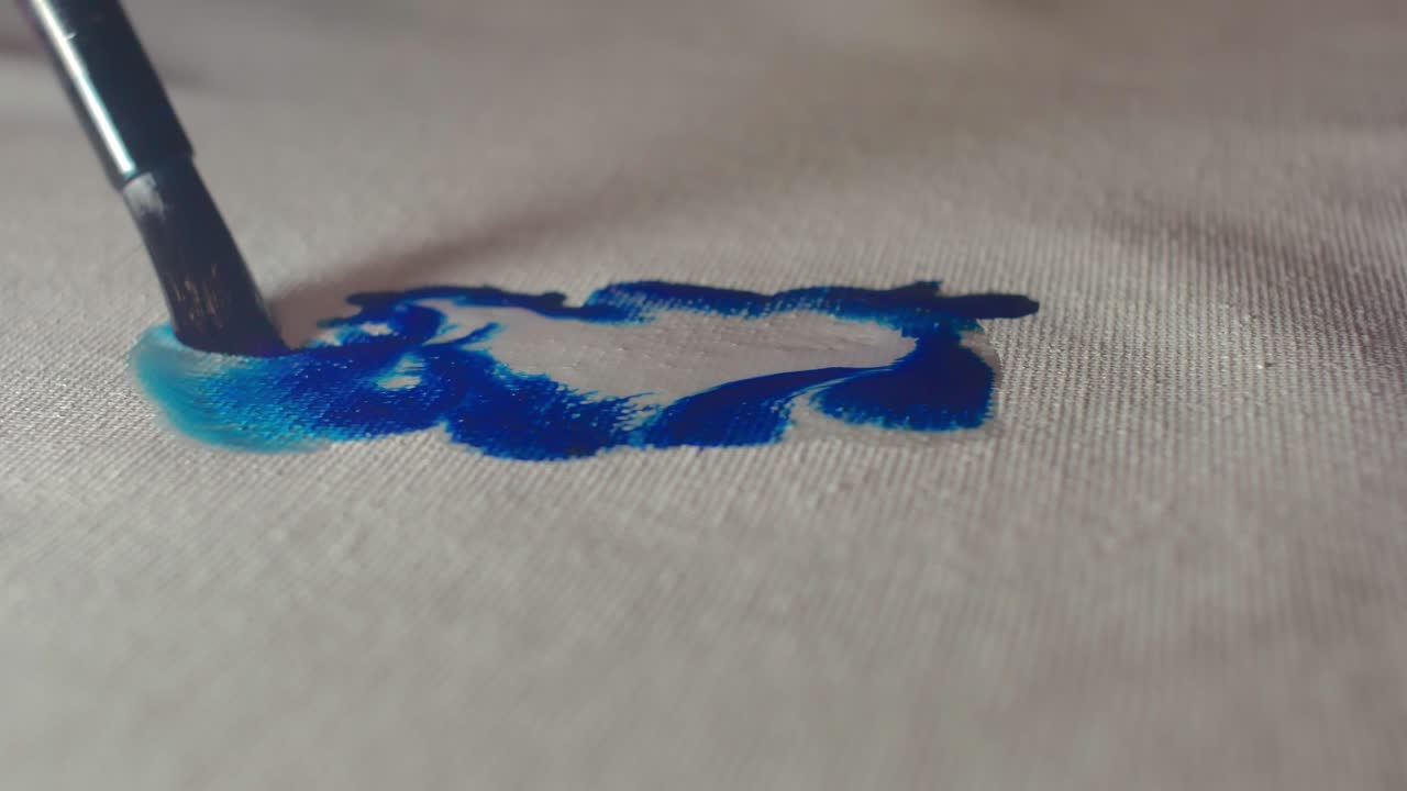 Close-up of an artist's brush applying blue paint to a white canvas. Ideal for art tutorials, creative studios, and fine art branding showcasing the tactile beauty of the creative process