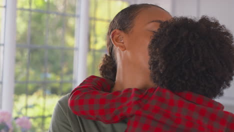 loving mother carrying and hugging son at home in family kitchen