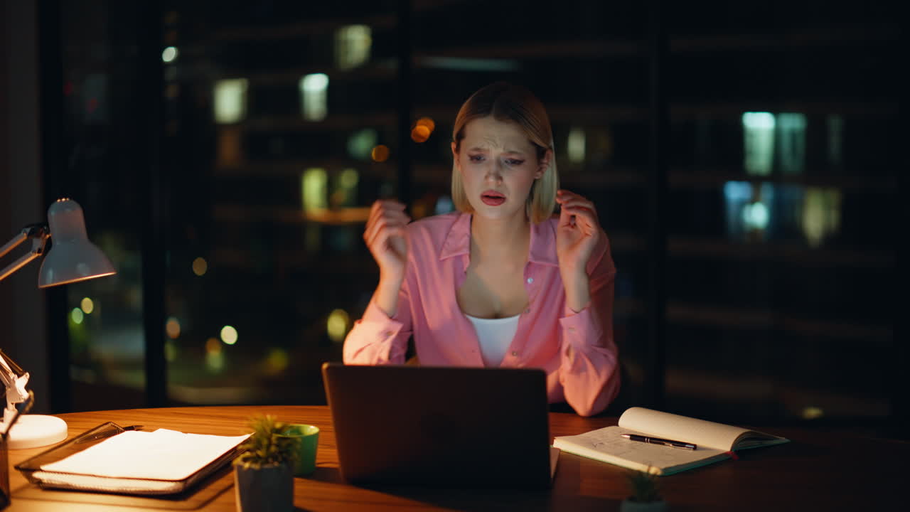 Donna preoccupata che lavora fino a tardi al computer portatile