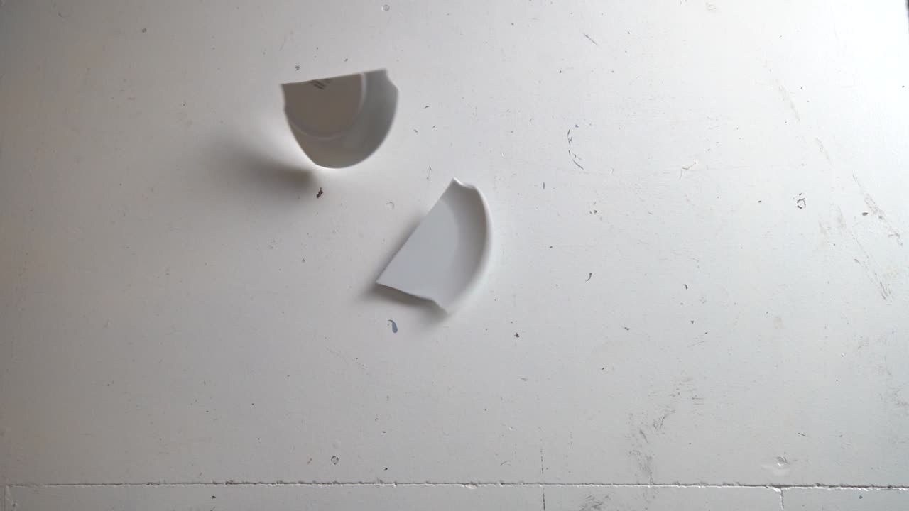 Smashing Plate Into Pieces On A Dirty Floor, Slow motion top down shot