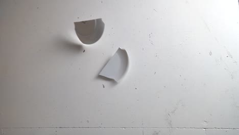 smashing plate into pieces on a dirty floor, slow motion top down shot