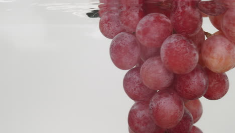 Un-Delicioso-Racimo-De-Jugosas-Uvas-Rojas-Sumergidas-En-Agua