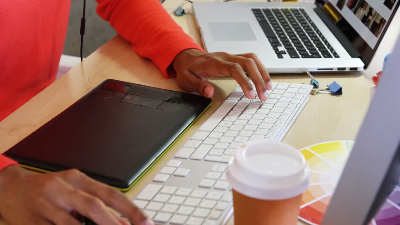 sección media de una diseñadora de moda usando una tableta gráfica en el escritorio en la oficina 4k