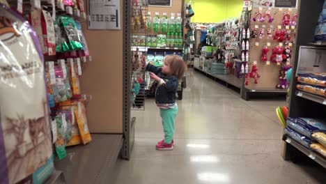 toddler walking wandering around at pet store aisle looking at goods.