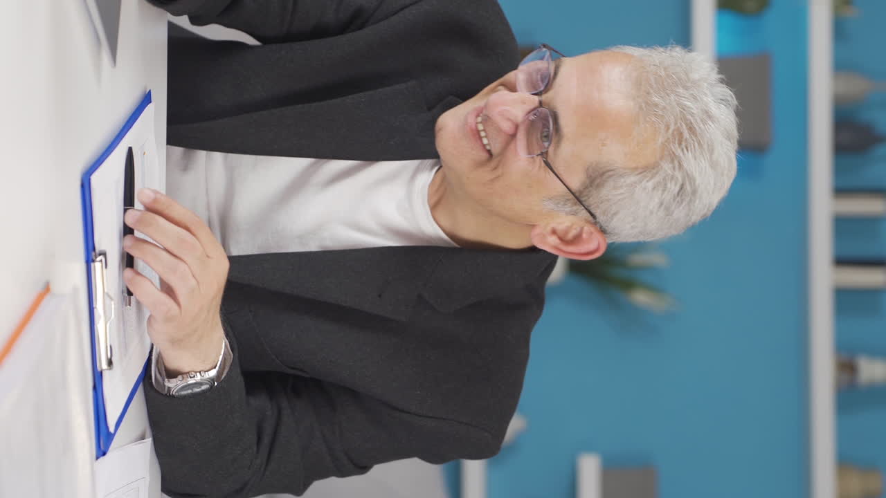 video vertical de un hombre que trabaja en una oficina en casa experimentando alegría.