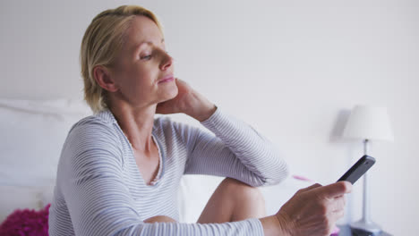 side view of caucasian woman using her phone on bed