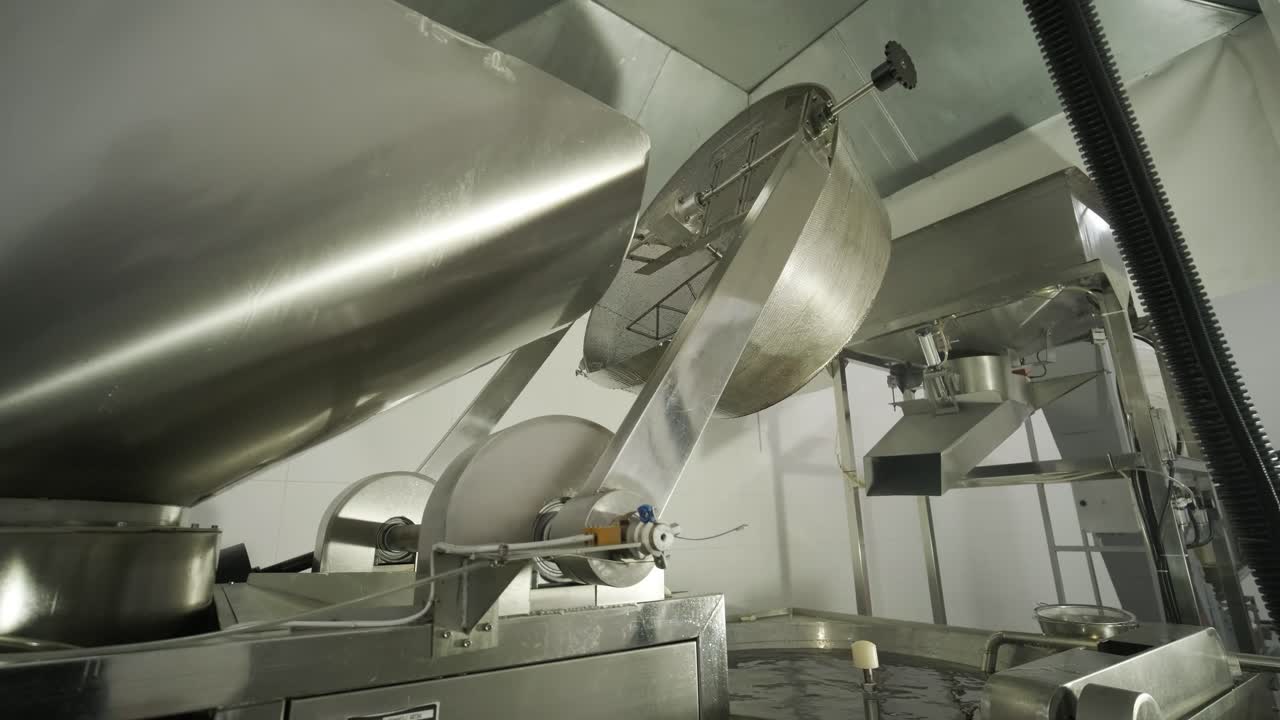 producción de papas fritas y bocadillos. máquina industrial de fritura profunda. las papas fritas se fríen en un cuenco grande con aceite. la línea de producción de la fábrica mueve las papas frias doradas después de freír.