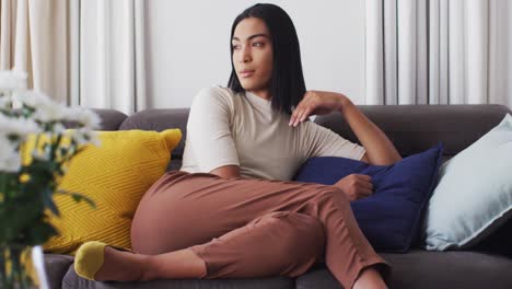 Gender-fluid-male-smiling-while-sitting-on-the-couch-at-home