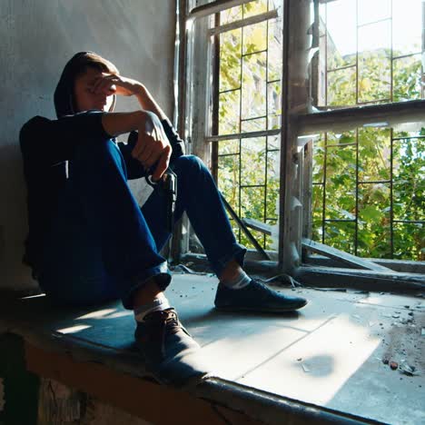 teenager with a gun sits in an abandoned building 2