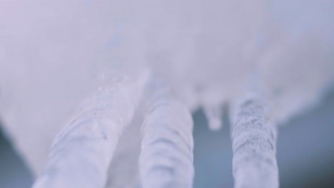 camera pans from an icicle where a drop falls in slow motion, close up