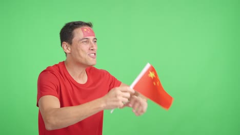 Man cheering for China waving a national flag looking away