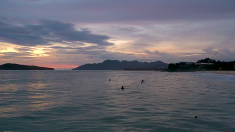 surfistas viendo la puesta de sol en la playa de pentai tengah, isla de langkawi, malasia