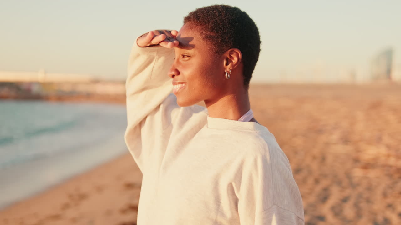 Joven afroamericana sonriendo en la playa durante la hora dorada