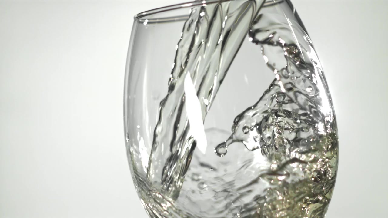 Vitt vin hälls i ett glas i slow motion