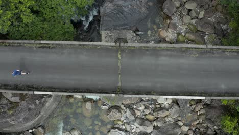 man running across bridge on yakushima island japan, top down aerial view
