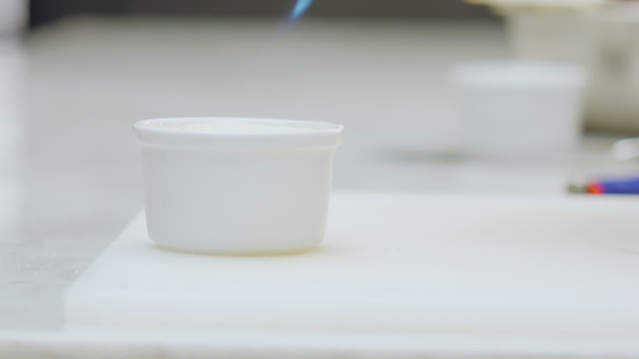 Close-up of a creme brulee dessert being torched with a culinary torch to caramelize its surface
