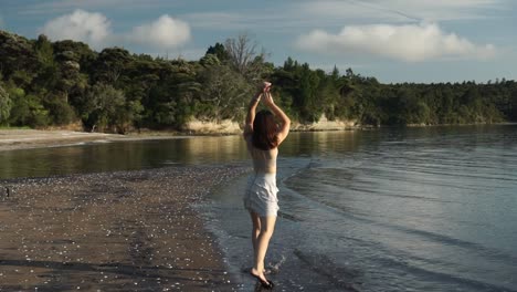 woman running and jumping on morning beach, back following gimbal view, slow motion