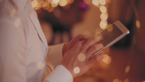 man touching digital tablet at illuminated home during christmas