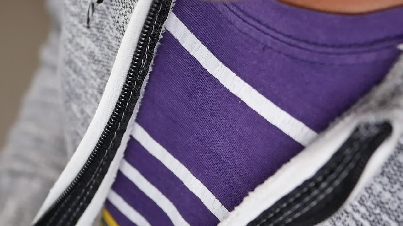 그 아래에는 보라색 줄무 셔츠가 있는 회색 후디의 클로즈업