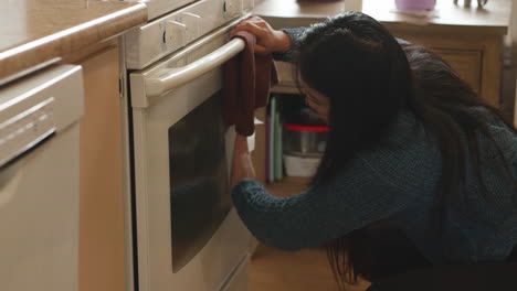 asian girl crouching, cleaning a white stove door, slow motion