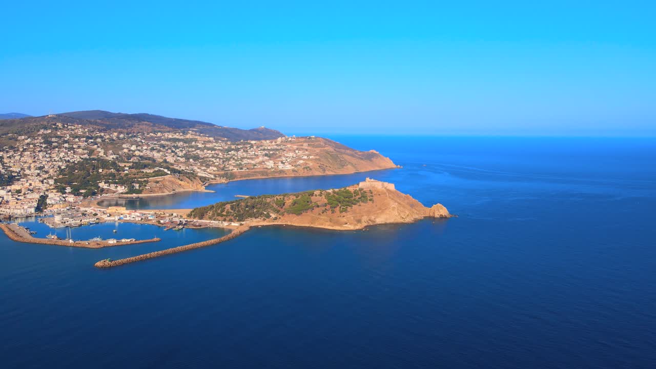 A beautiful ocean shore with mountains in the background, white clouds and clear skies make for a perfect day at the beach.