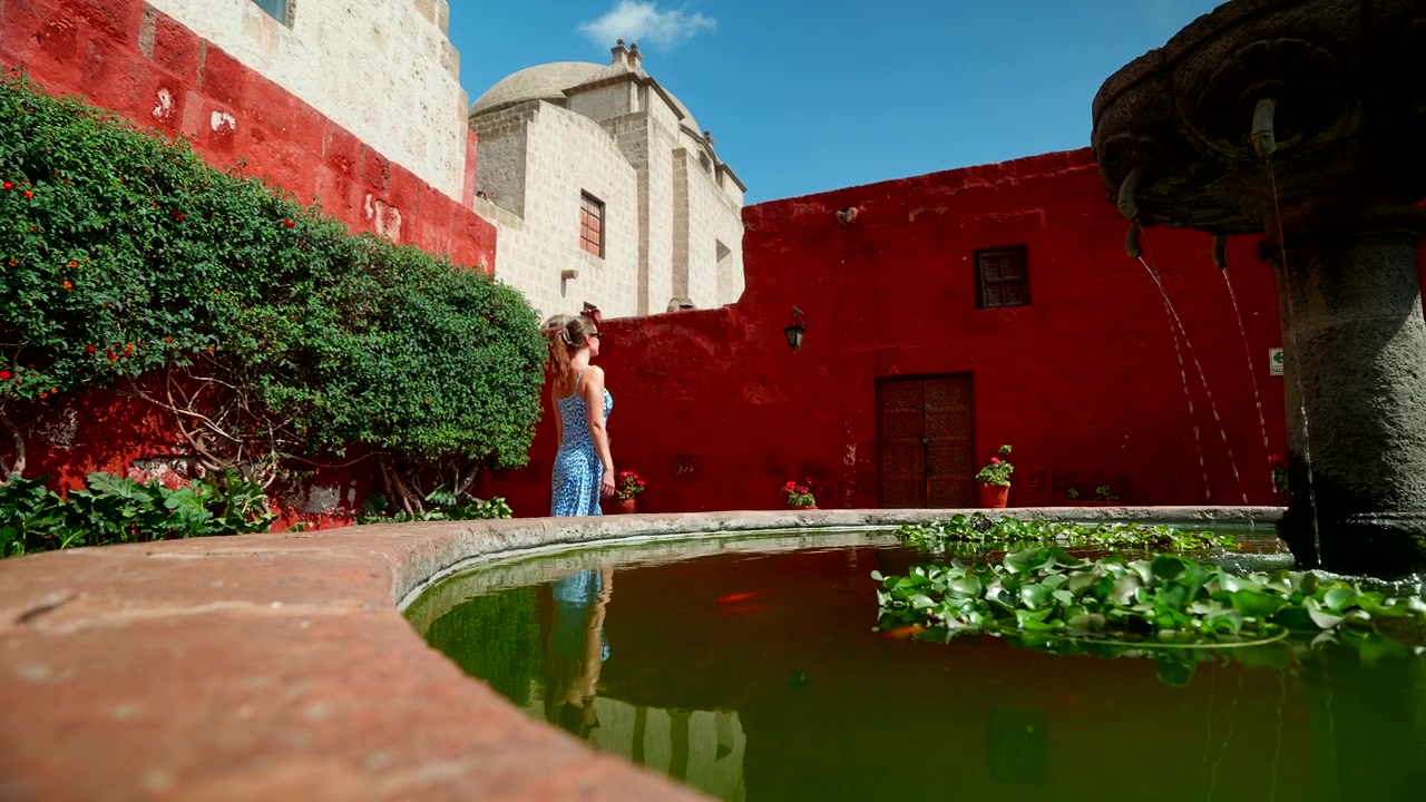 Arequipa, Peru'daki Santa Catalina Manastırı'nın Canlı Kırmızı Duvarlarını ve Taş Çeşmesini Keşfeden Genç Bir Kadın Turist. Turizm ve Mimari Miras Temaları İçin Yüksek Kaliteli Seyahat Görüntüleri