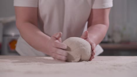 female hands knead and toss dough on kitchen