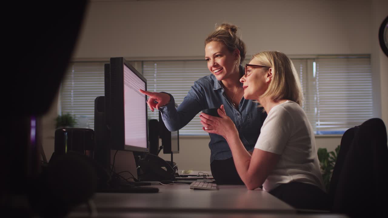 dos mujeres de negocios teniendo una reunión informal sentadas en el escritorio en la oficina trabajando hasta tarde