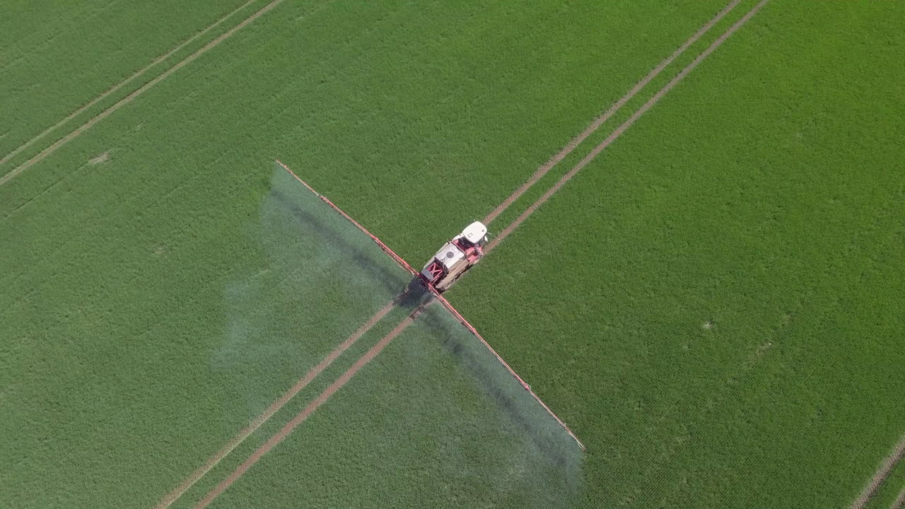 Vista aerea di un agricoltore che irrora le colture in un campo nell'Aberdeenshire in una giornata di sole, Scozia.