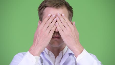 portrait of young man doctor covering eyes