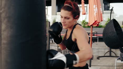 strong athletic female boxer in gloves punching a bag. workout outside. female boxer training. self defence concept