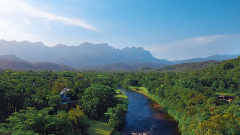 Hermosa-Vista-Aérea-De-Un-Río-Brasileño-En-Un-Bosque-Verde-Tropical-Con-Montañas-En-El-Fondo