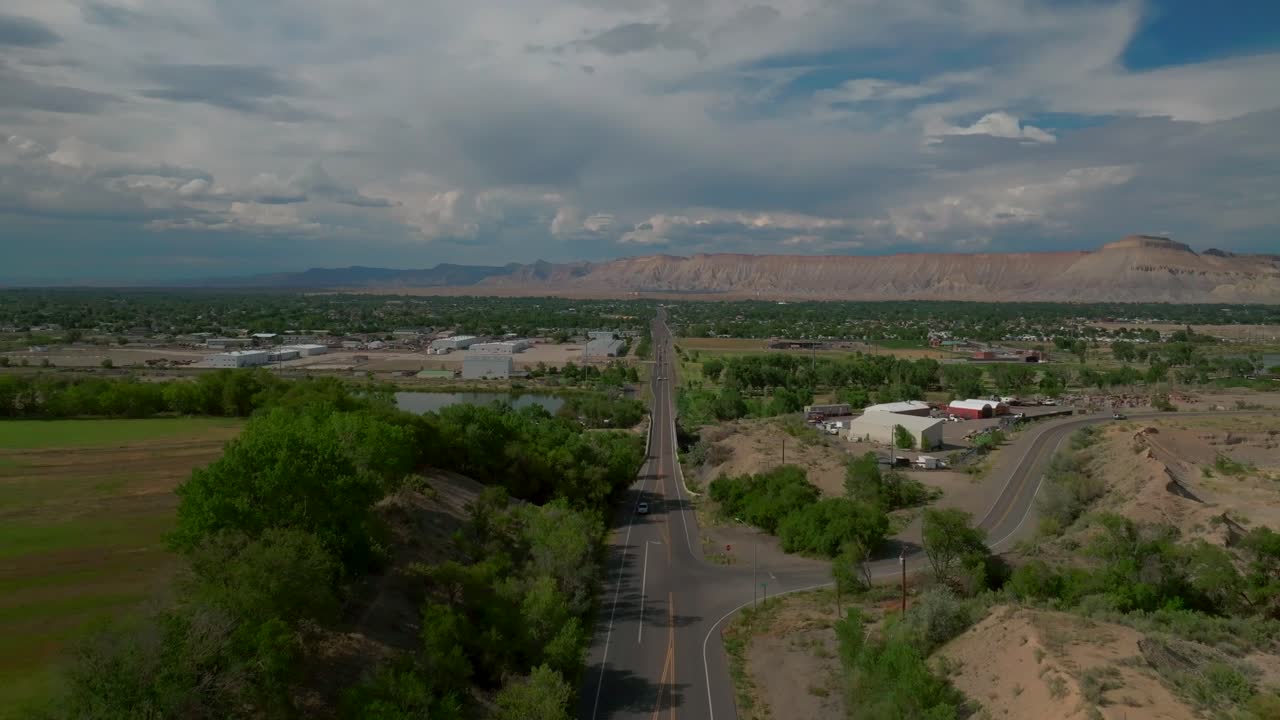 Grand Junction Colorado river aerial drone forward pan up motion Summer Grand Mesa downtown Main Street afternoon cloudy blue sky wine vineyards Parachute Fruitvale Mt Garfield Western Close Delta USA