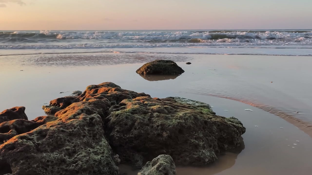 Peaceful Ocean Waves and Rocks on a Sandy Beach at Golden Hour