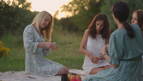 a group of young women are intently sculpting clay in a meadow in a field in a park in an open space talking. creative activities women's circle communication joint pastime.