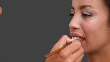 make up artist putting lip gloss on models face