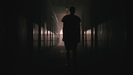 a bald man walks on the empty hospital corridor at night