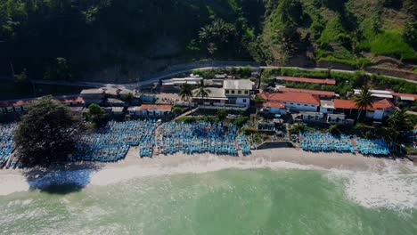 Exotic-village-coastline-with-blue-fisherman-boats,-aerial-drone-view