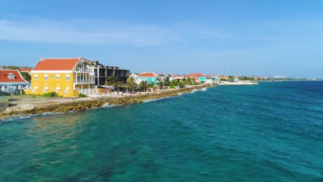 rocky coastline of willemstad curacao with vibrant yellow building facades by beautiful caribbean ocean water