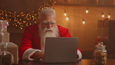 Alegre-Santa-Trabajando-En-Una-Computadora-Portátil.-Papá-Noel-Usando-El-Primer-Plano-De-La-Computadora-Portátil.-Imágenes-4k-De-Alta-Calidad