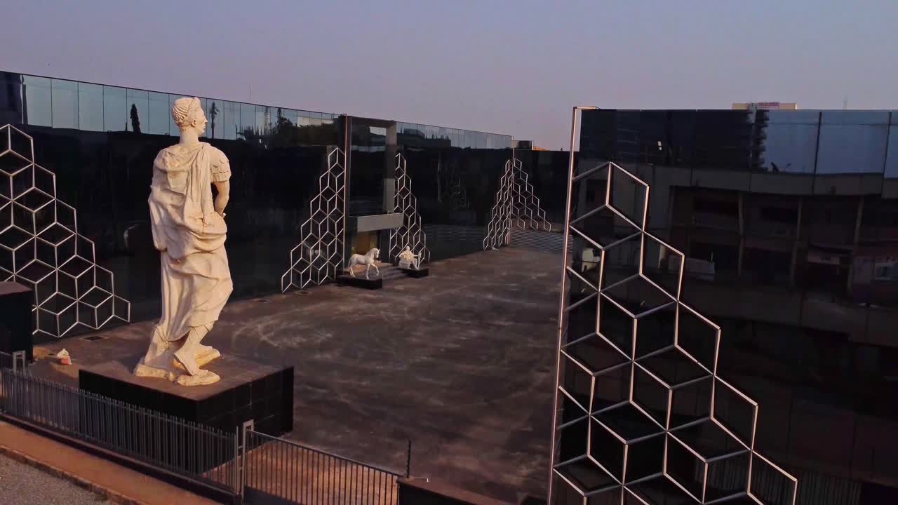 Jib up of a beautiful statue overlooking the courtyard in front of a modern office building in Abuja, Nigeria